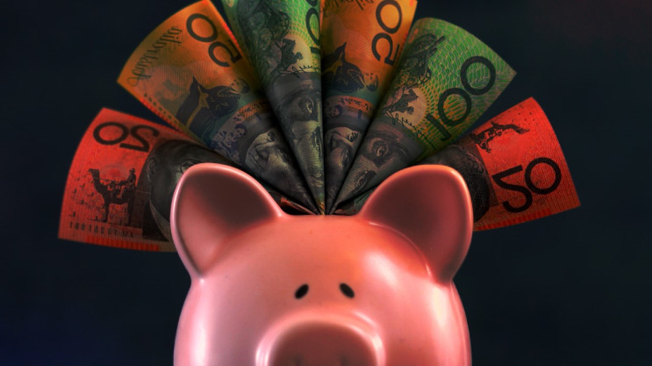 A piggy bank showing different Australian dollars bills sticking out.