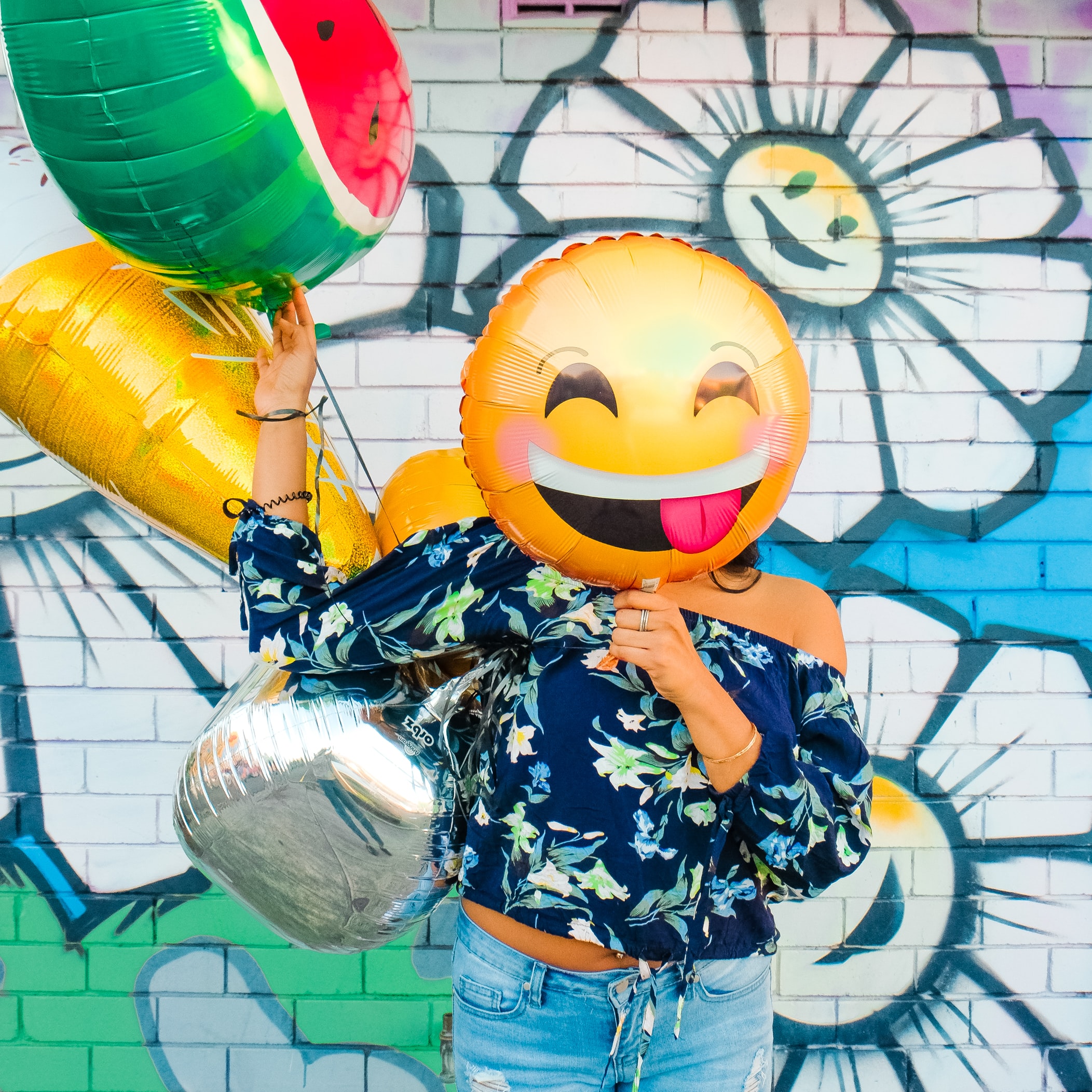 A woman holding emoji balloons
