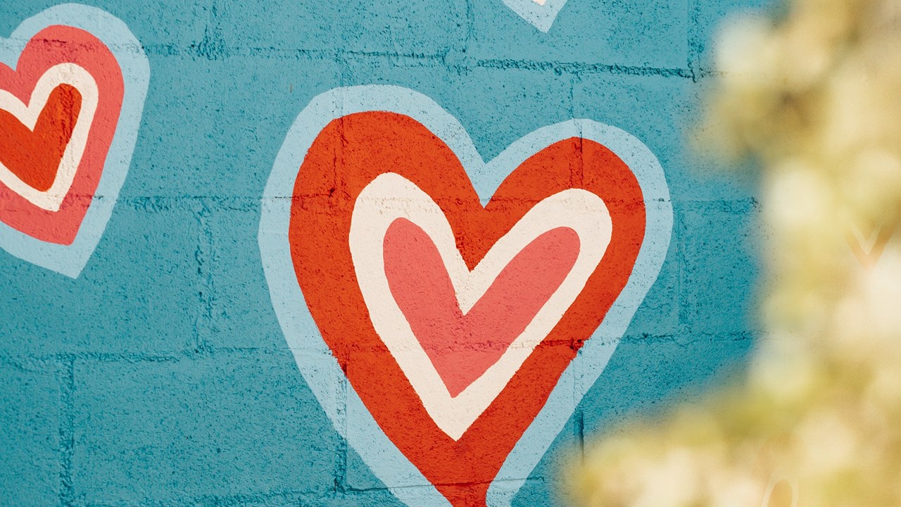 Painting of a heart on a blue brick wall