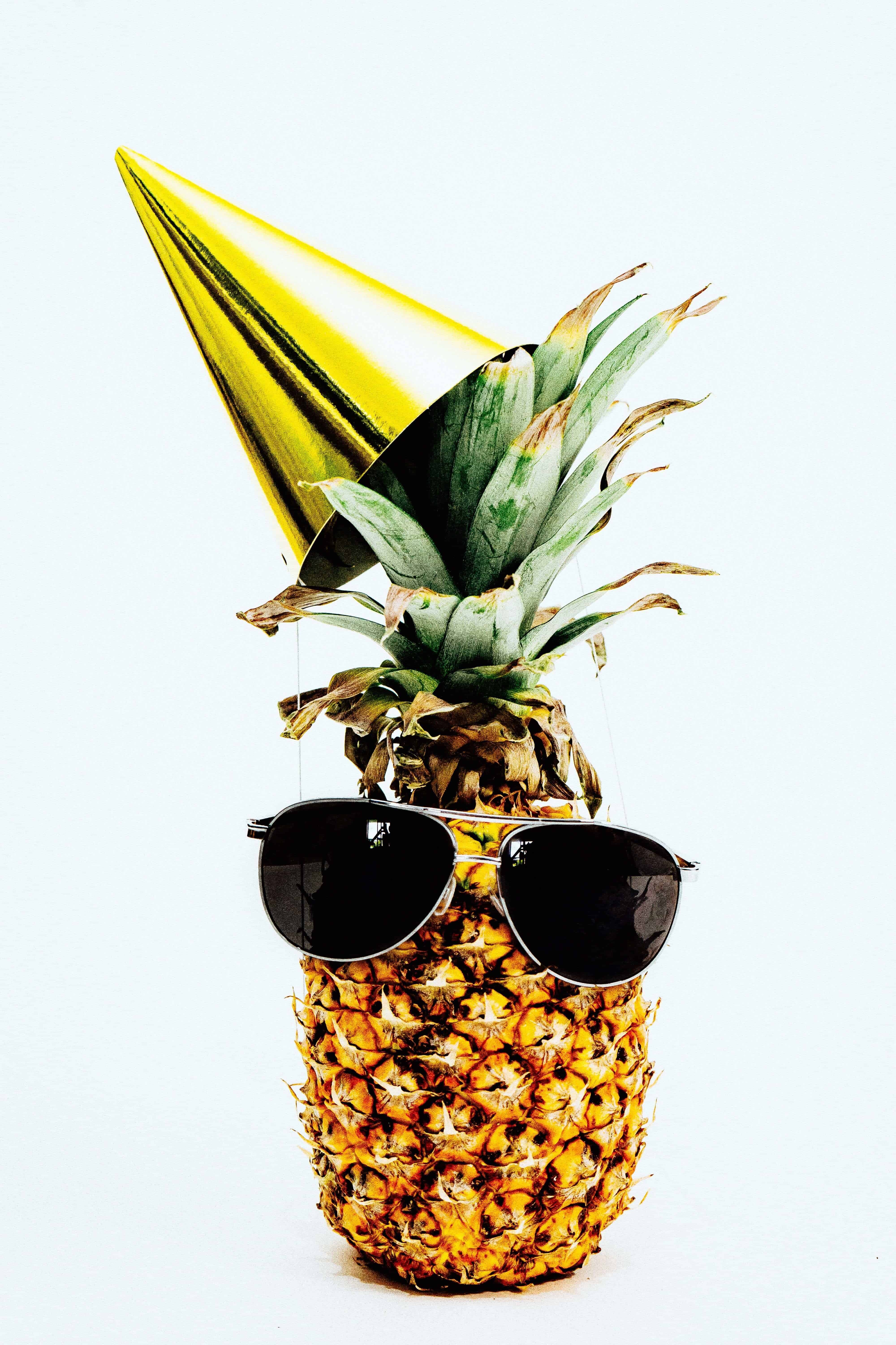 A pineapple wearing sunglasses and a party hat
