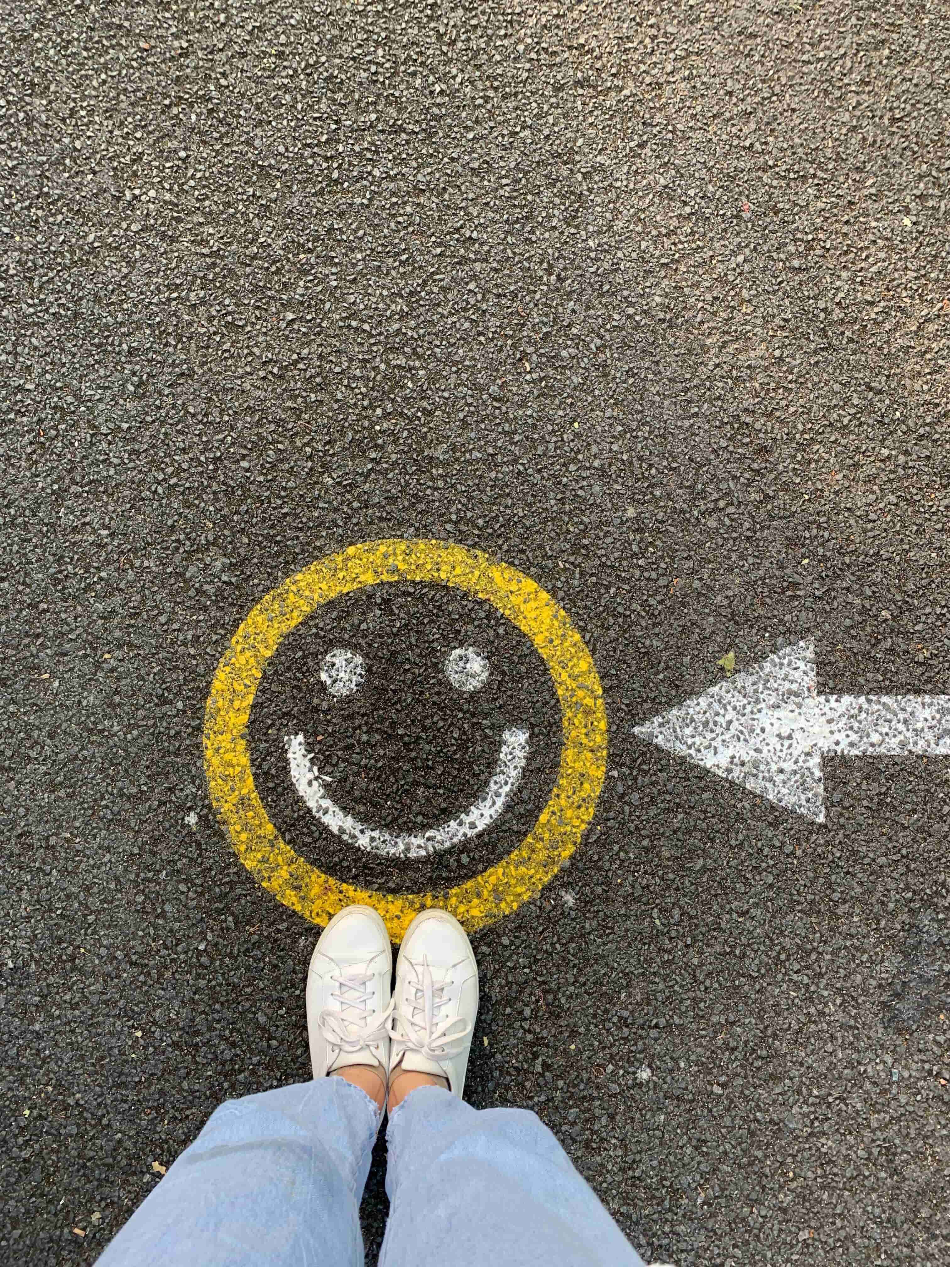 Someone standing in front of a smiley face on the pavement