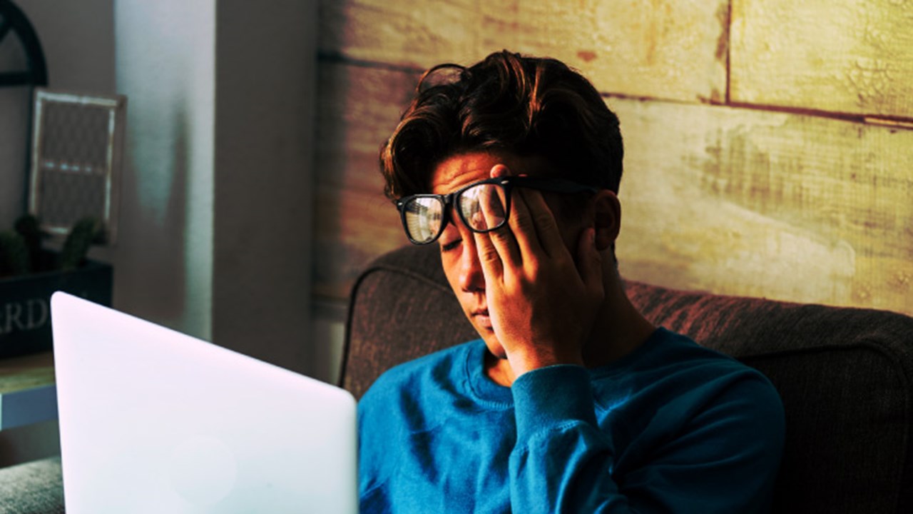Stressed student at home studying with personal laptop computer